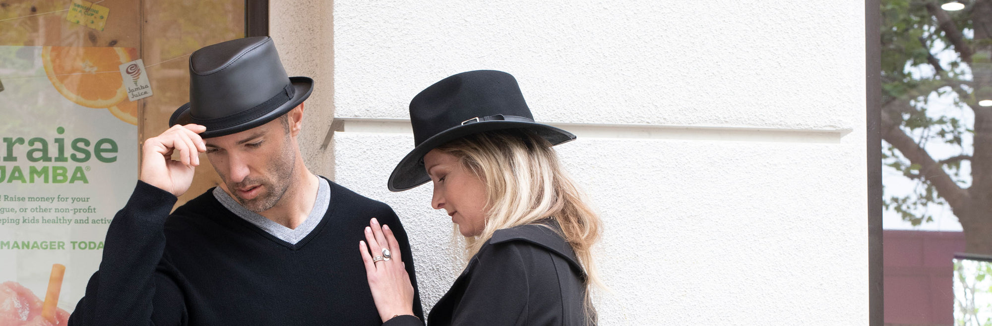 man wearing a black trilby stingy brim fedora and a woman wearing a black fedora