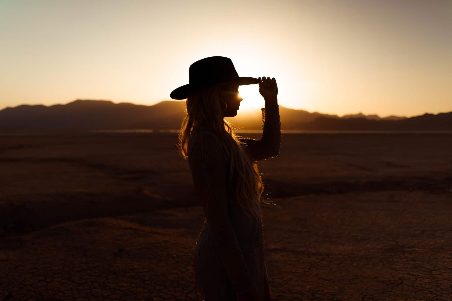 A woman wearing a cowboy hat during sunset