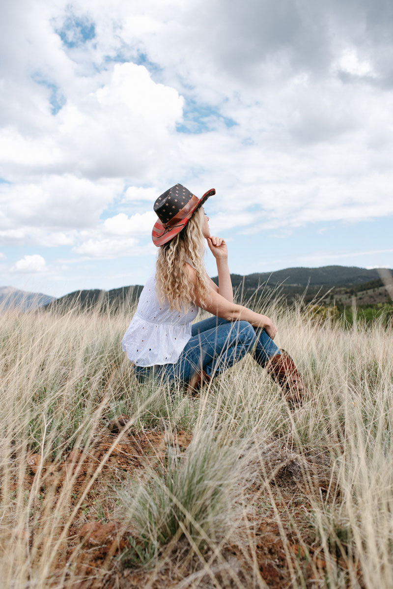 A woman on the grass wearing a straw cowboy hat