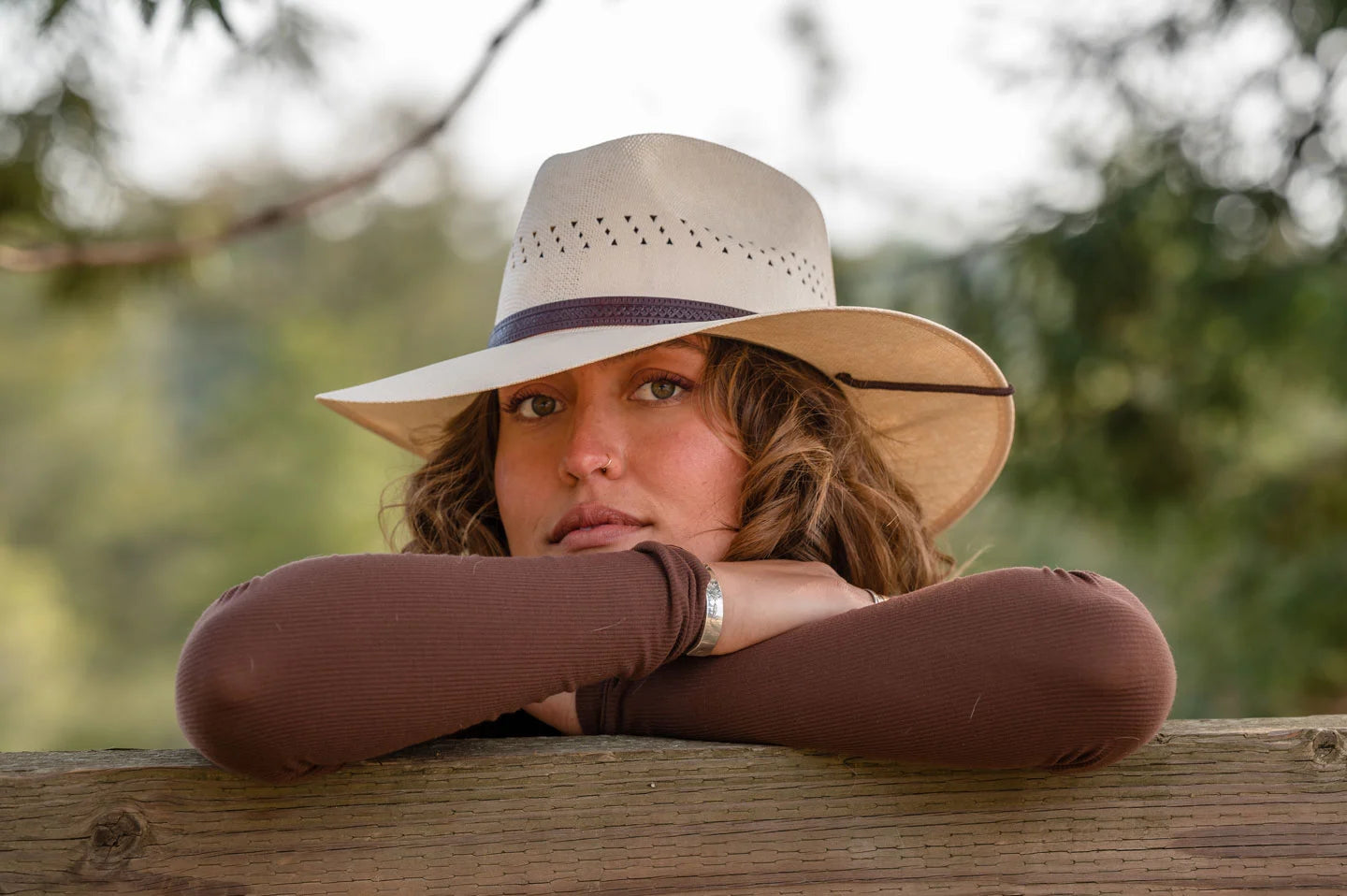 woman on a fence wearing the barcelona straw sun hat by American Hat Makers