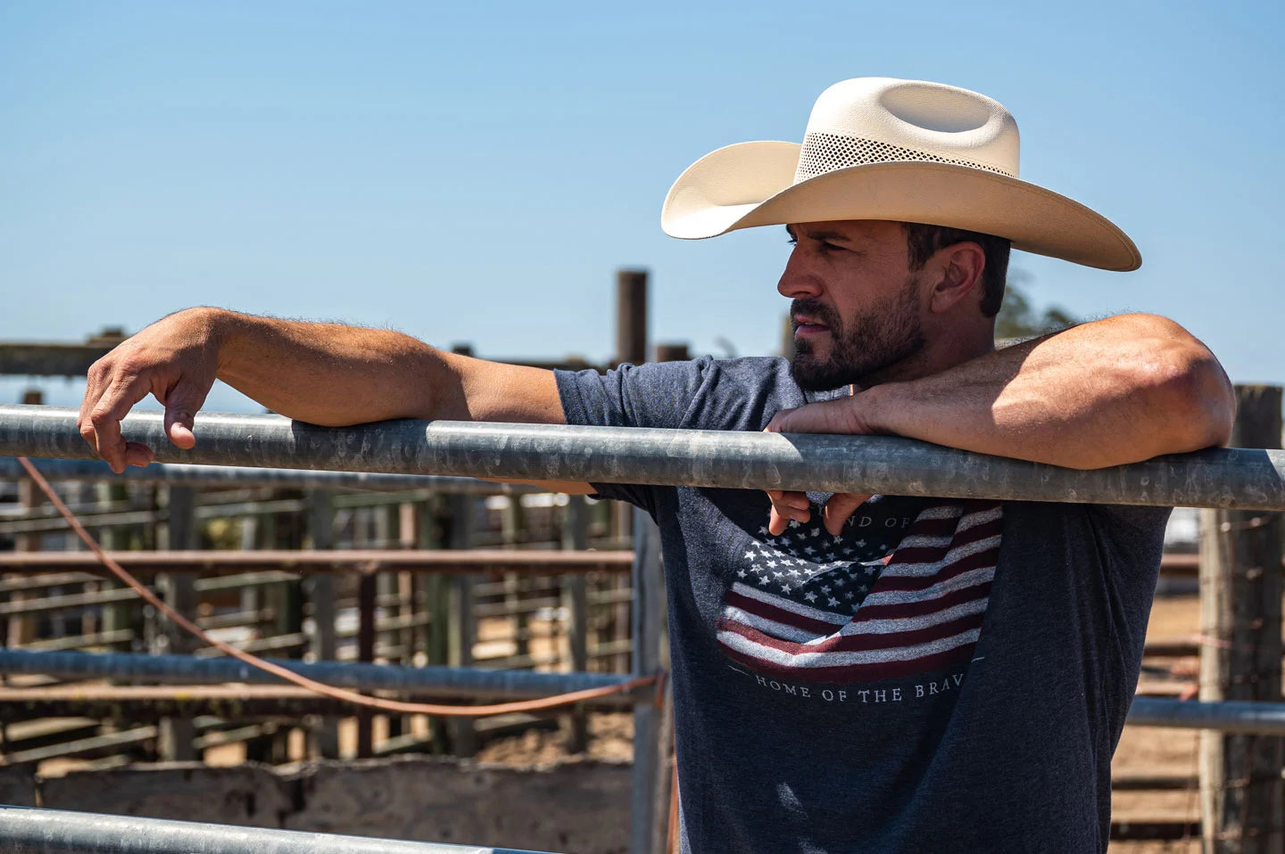 Cowboy leaning on fence wearing the Big Sky white cowboy hat by American Hat Makers