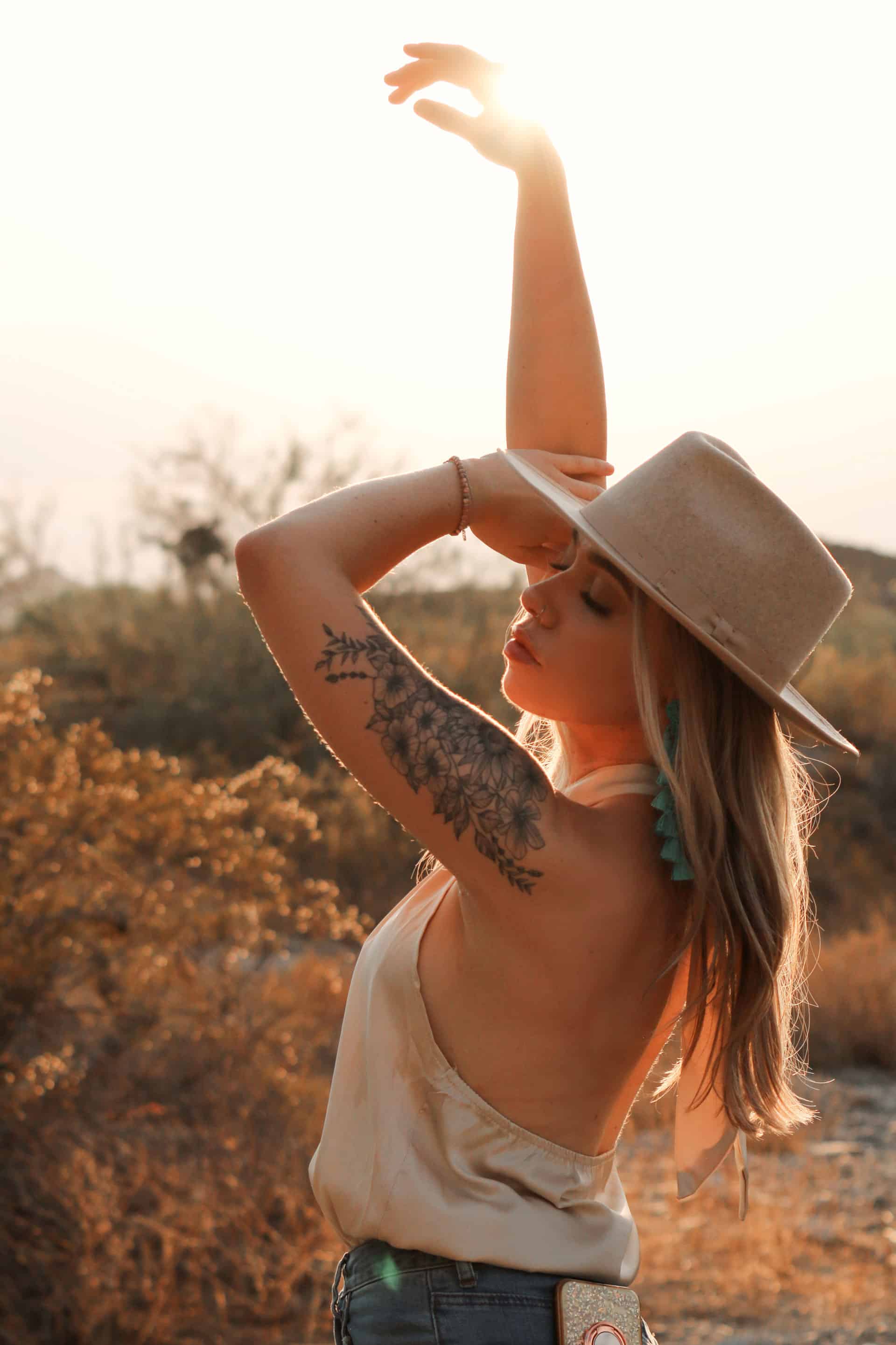 woman wearing a cream colored felt fedora at sunset