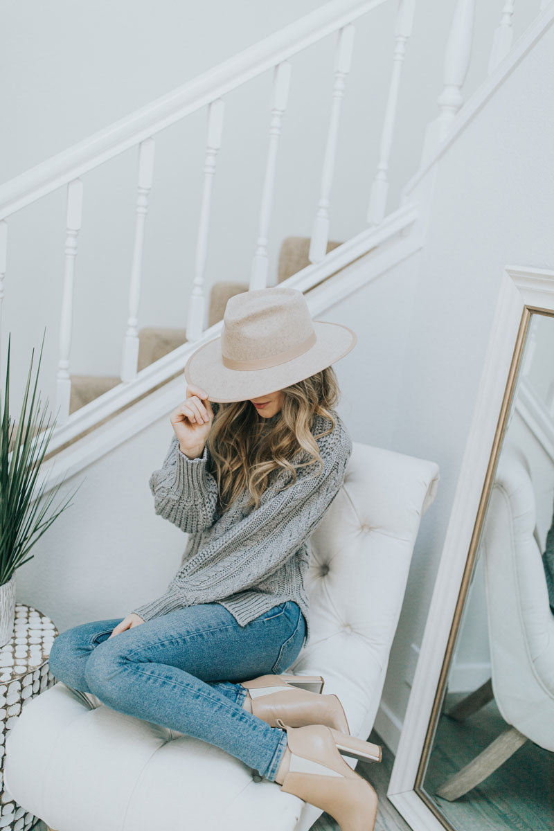 A woman sitting on a couch wearing a bondi wide brim hat