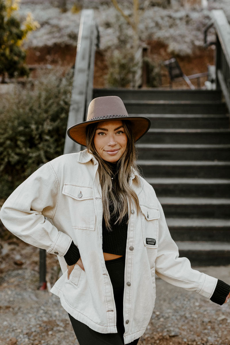 A woman standing outdoors wearing a mesh leather sun hat