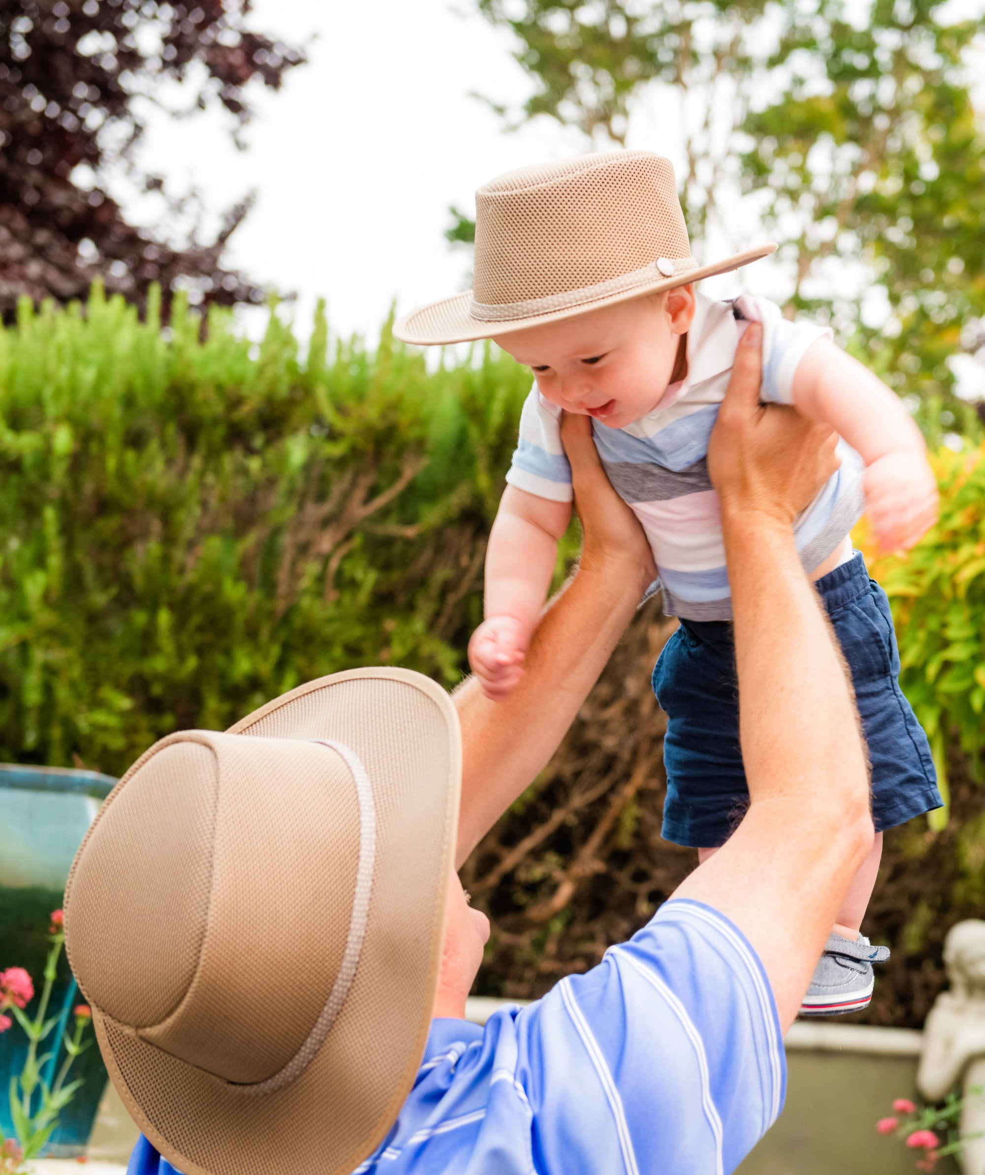 A man lifted a kid wearing a sun hat