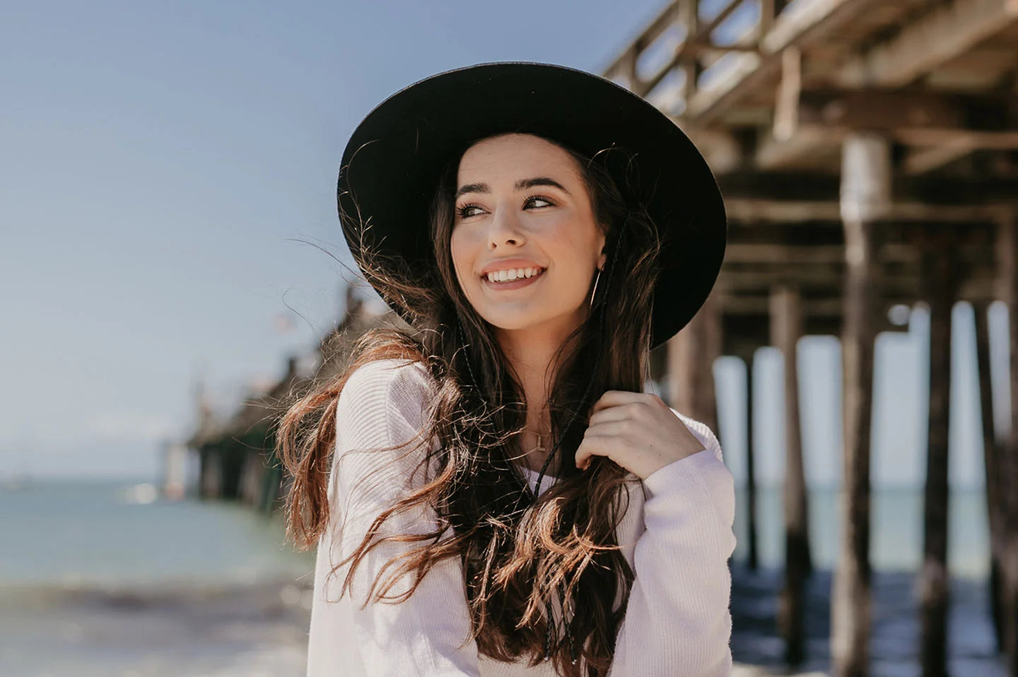 woman at the pier wearing a black felt boater hat by american hat makers