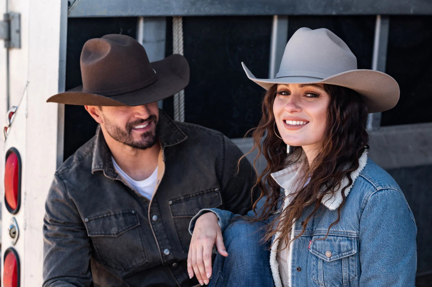 Man and Woman sitting on trailer while wearing the Cattleman yellowstone cowboy hats by American Hat Makers