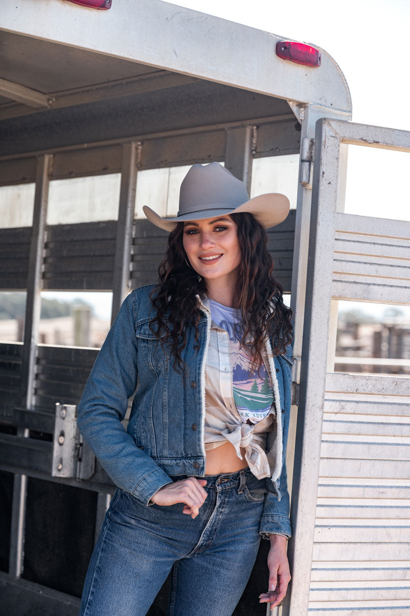 A woman wearing a sand felt cowboy hat while on a truck