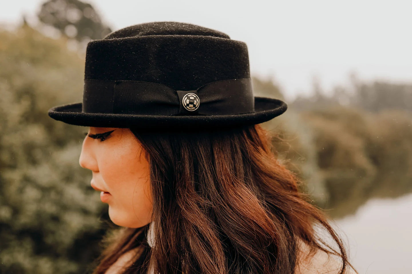 woman with trees at the back wearing black hat by american hat makers