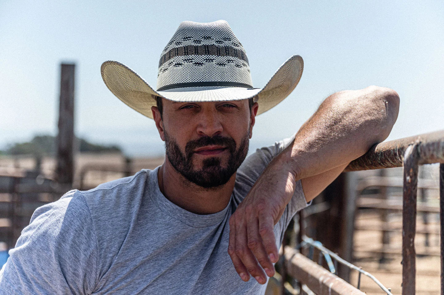 Man leaning against fence wearing the cisco cream straw cowboy hat by American Hat Makers