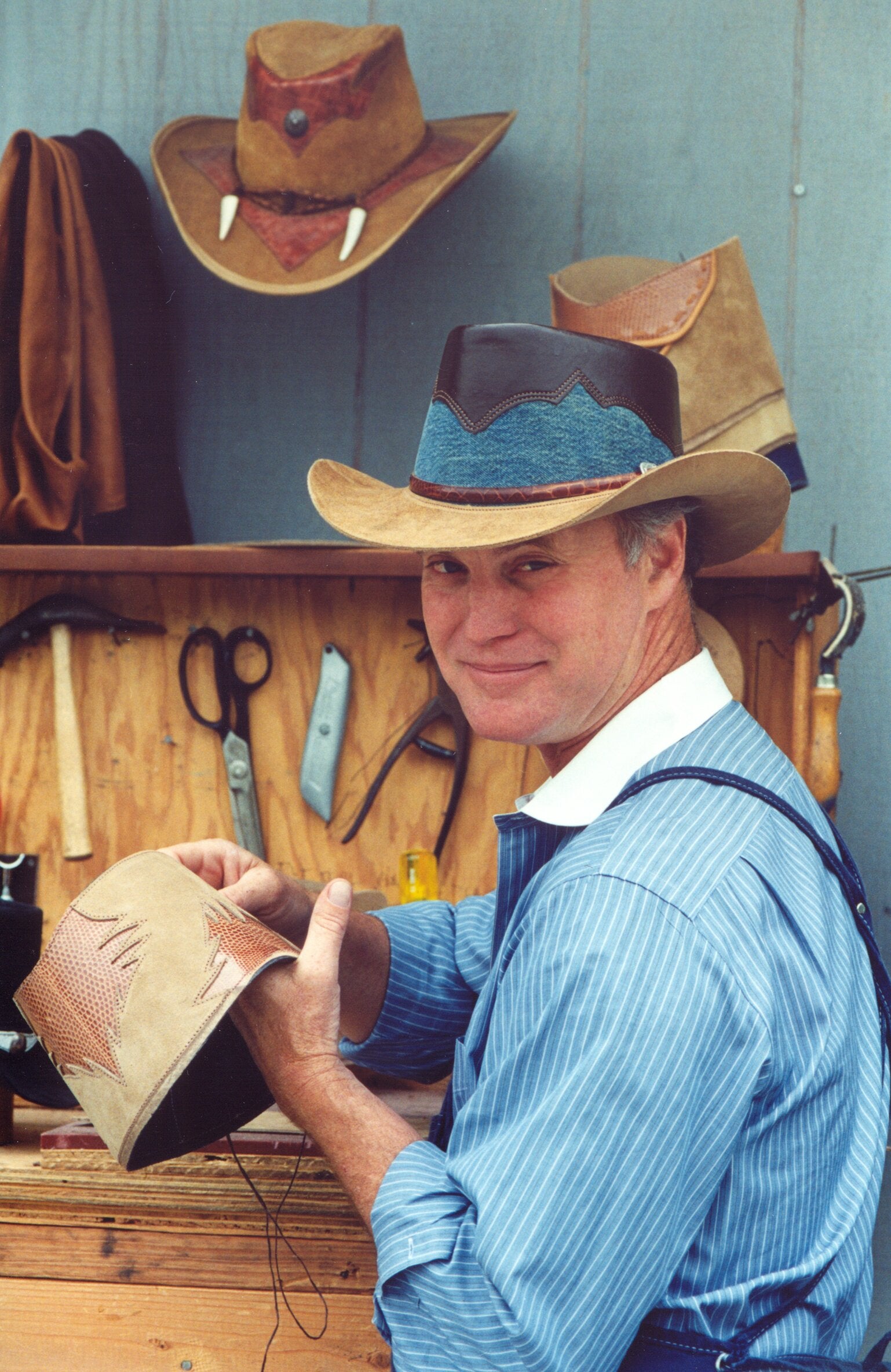 A man working wearing a blue polo and a cowboy hat 