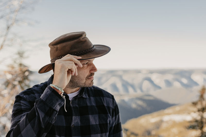 A man in a checkered polo wearing a bomber brown leather hat