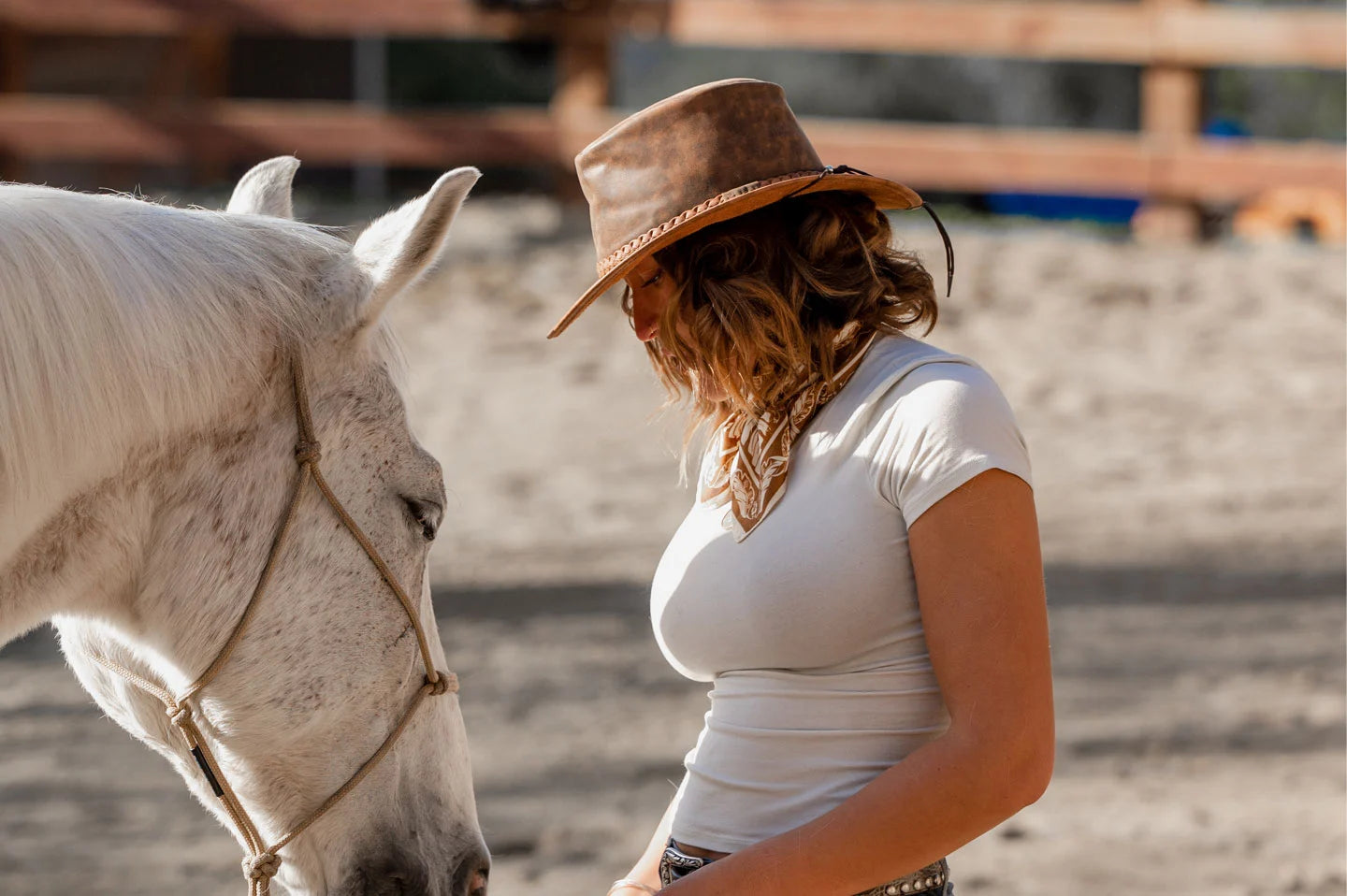woman in white feeding the horse wearing a brown leather hat by american hat makers