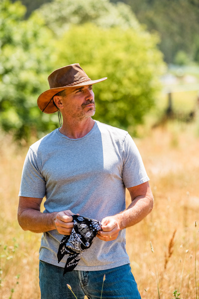 A man on the field holding a handkerchief wearing a copper leather hat