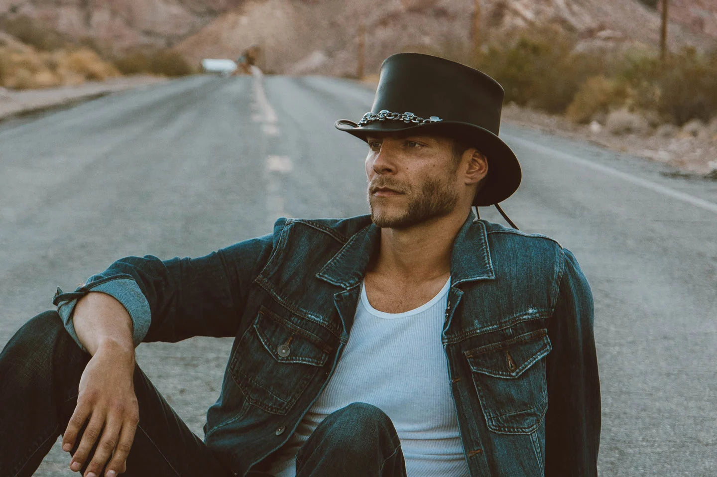 Man sitting on road wearing the El Dorado 5 Skull mens top hat by American Hat Makers