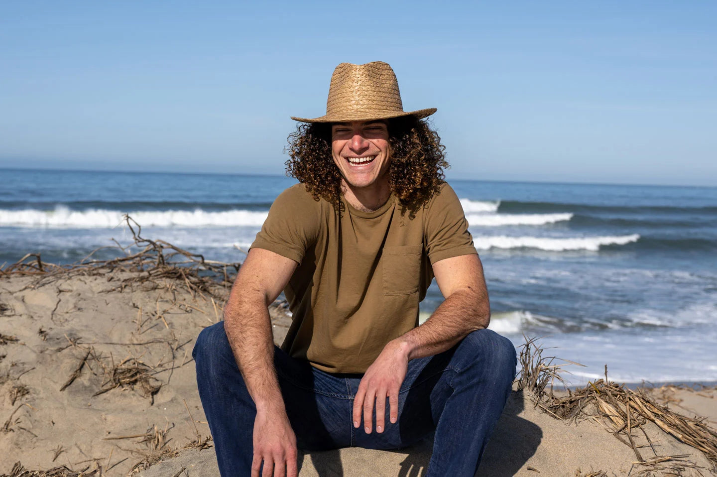 Man sitting at beach wearing the Fabian mens straw hat by American Hat Makers