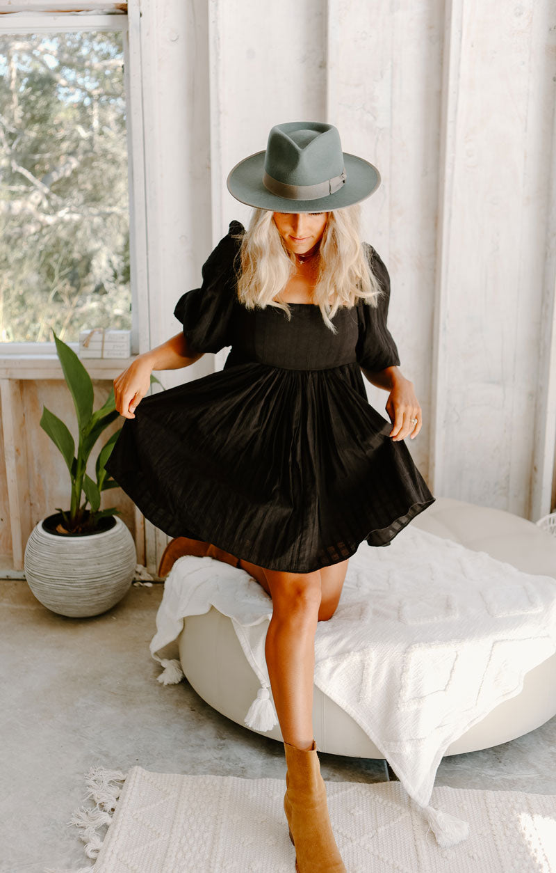A woman in a black dress wearing a geneva rhino felt hat