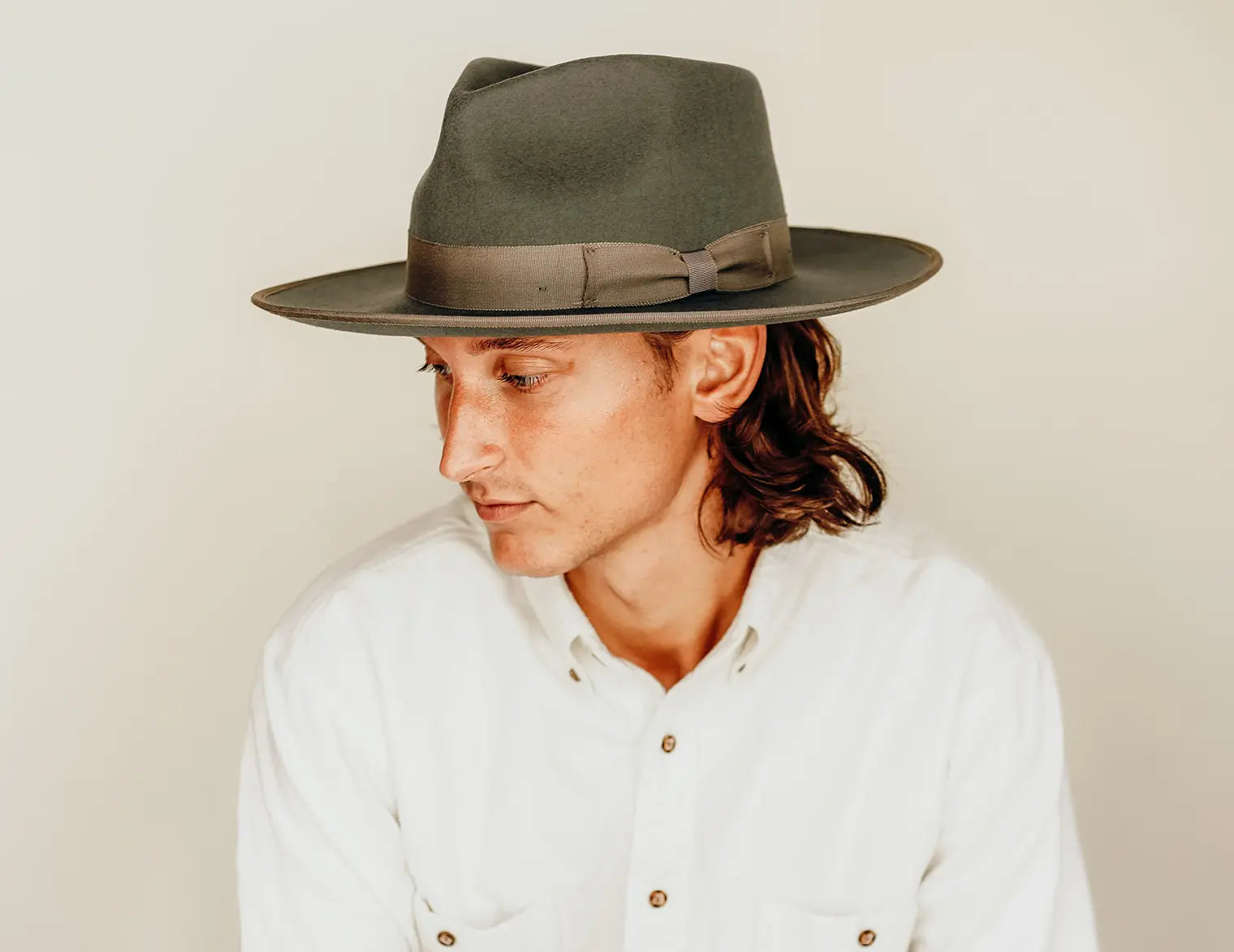 A man looking at the side wearing a white polo and a black hat