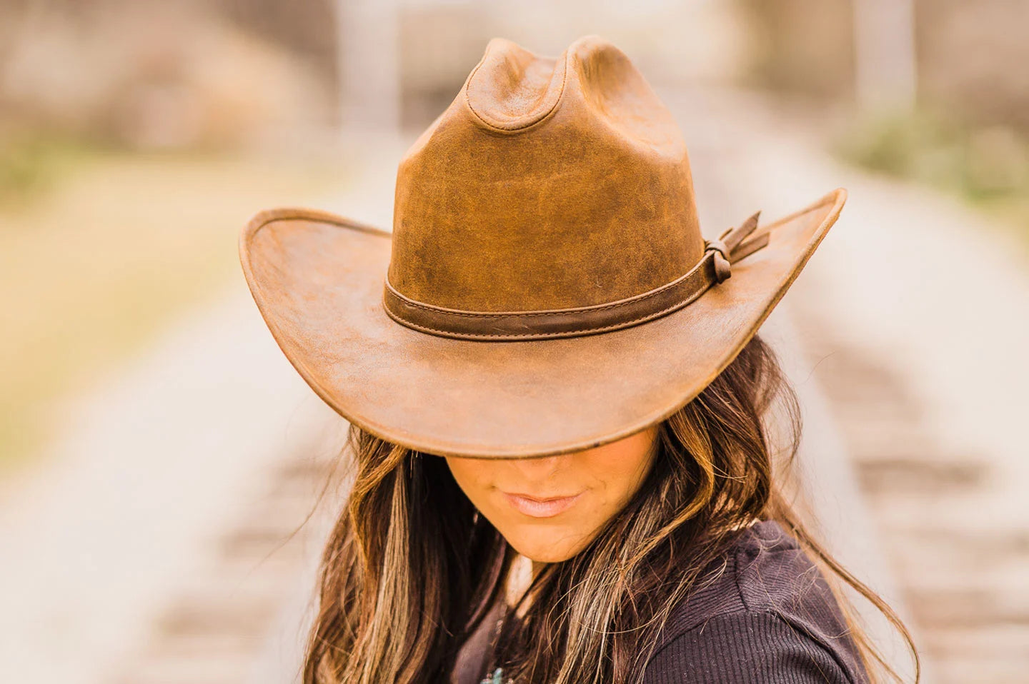 woman standing in the middle of the rail track wearing a brown leather hat by american hat makers