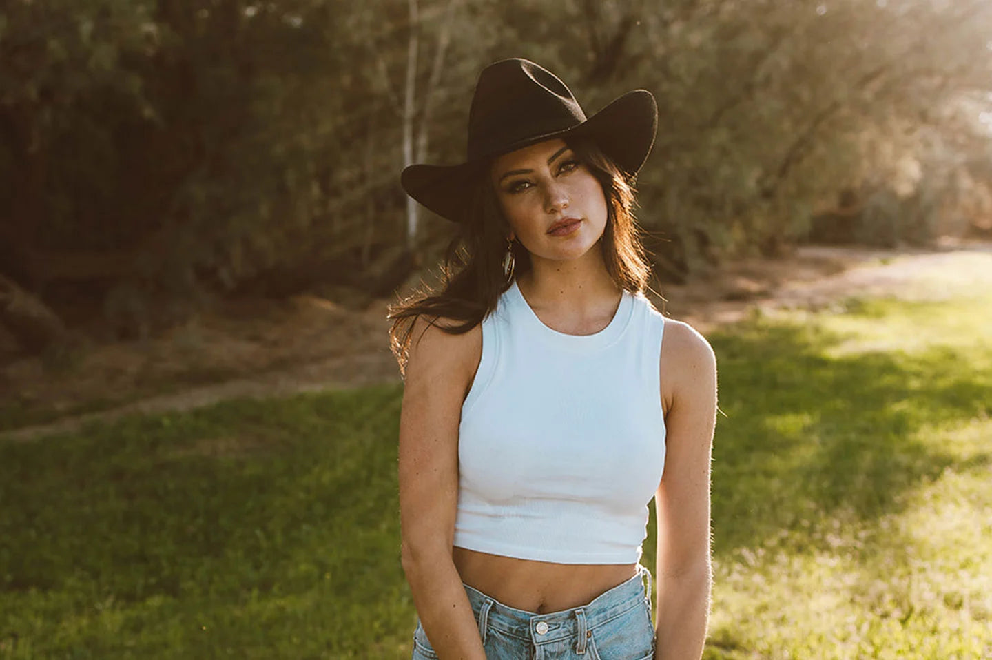 woman in white standing outside wearing a black hat by american hat makers