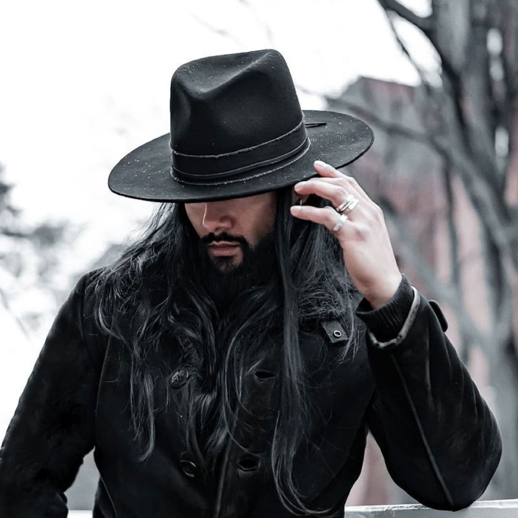 A man in his black jacket holding a black felt hat