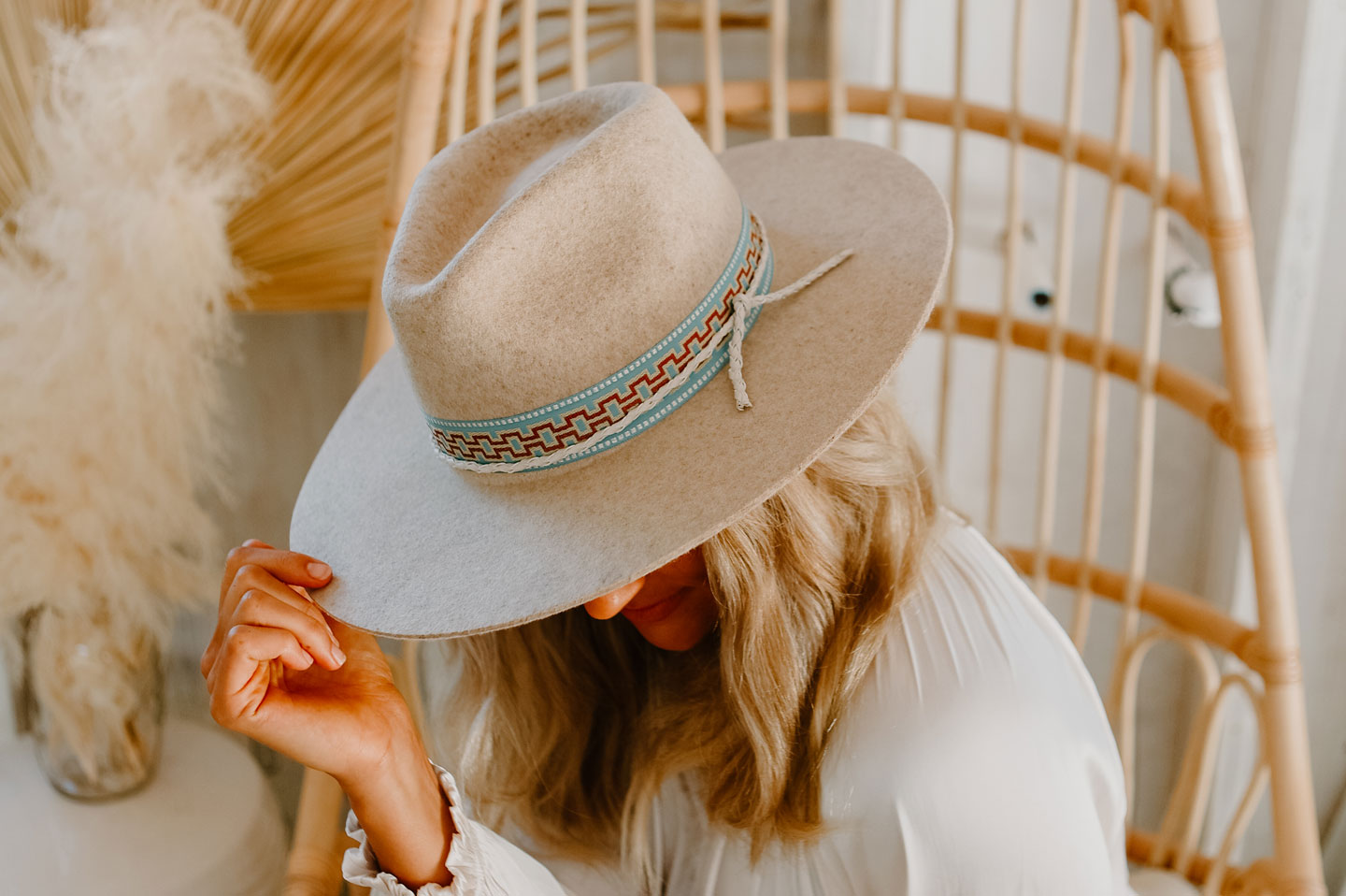 woman sitting on a wicker chair wearing a felt fedora