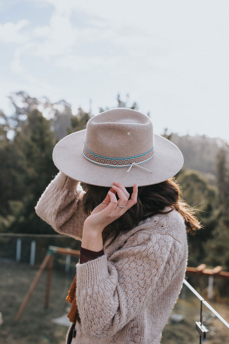 A woman wearing a knitted jacket and a Oatmeal wide brim hat