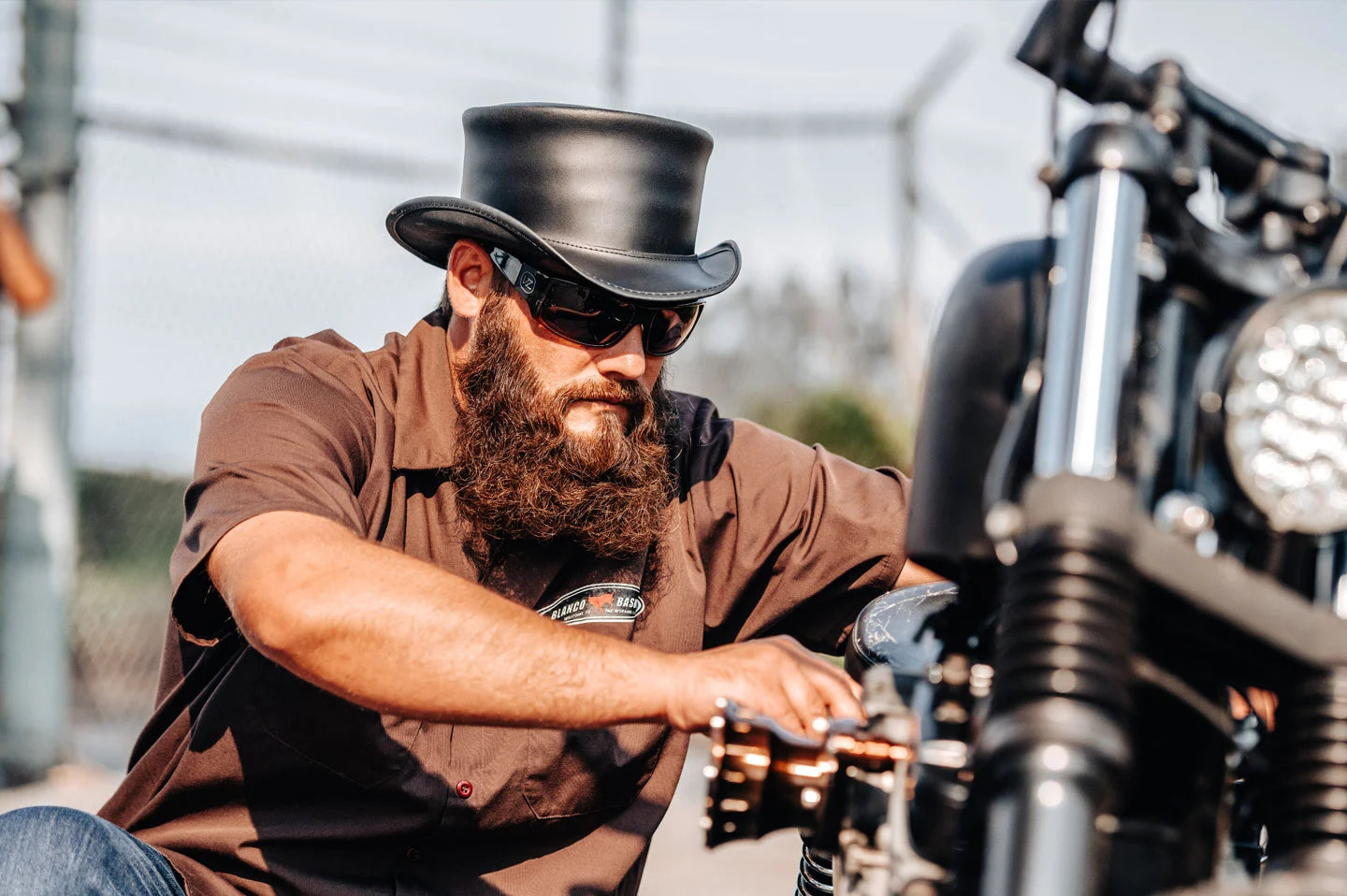 Man fixing motorcycle while wearing the Unbanded Marlow black mens top hat by American Hat Makers