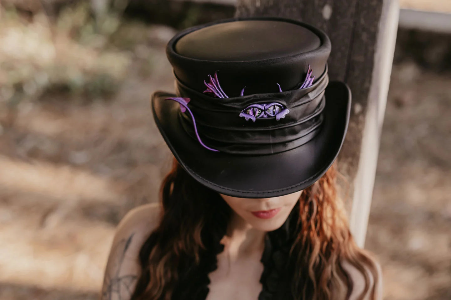 woman leaning on a piece of wood wearing voodoo top hat by american hat makers
