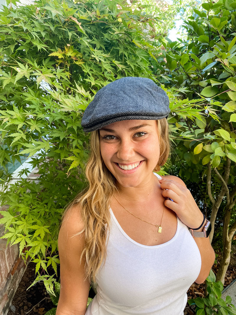 A woman with plants behind her wearing mikey charcoal cap