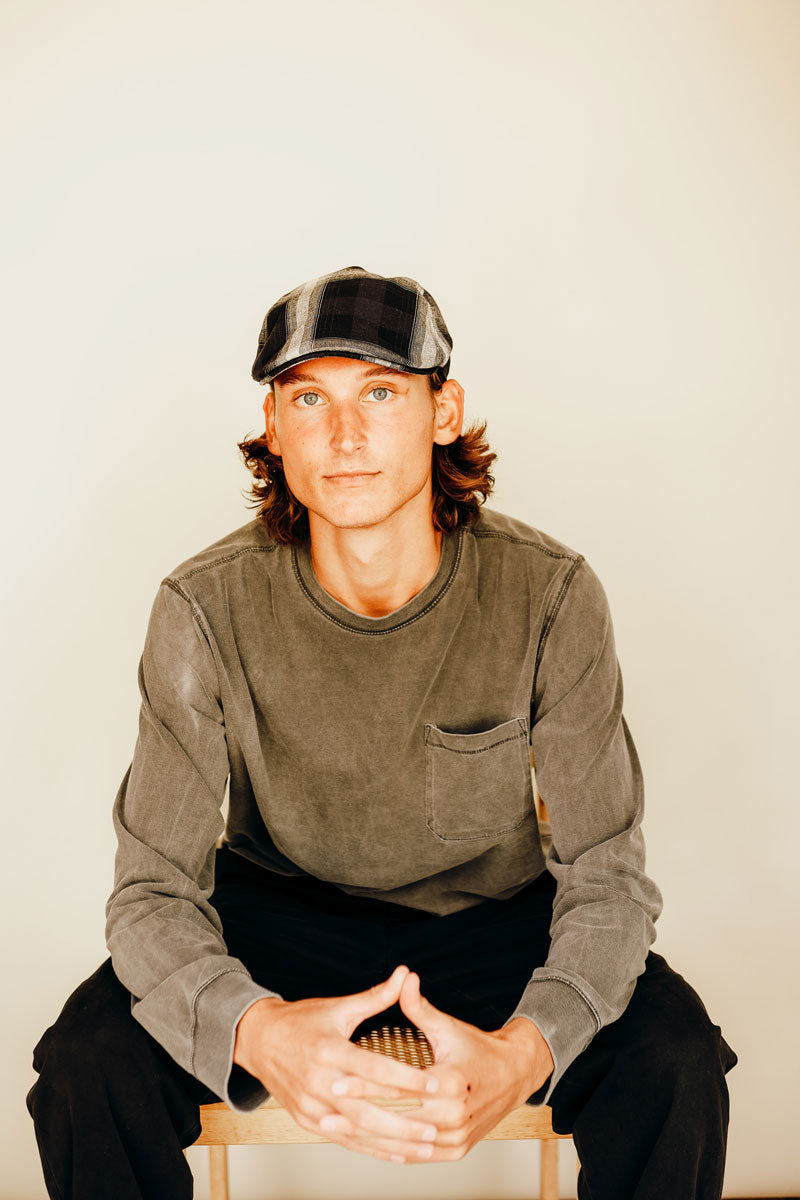 A man sitting down and facing front wearing a navy cap