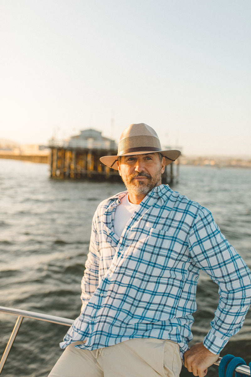 A man on the boat wearing tan sun hat