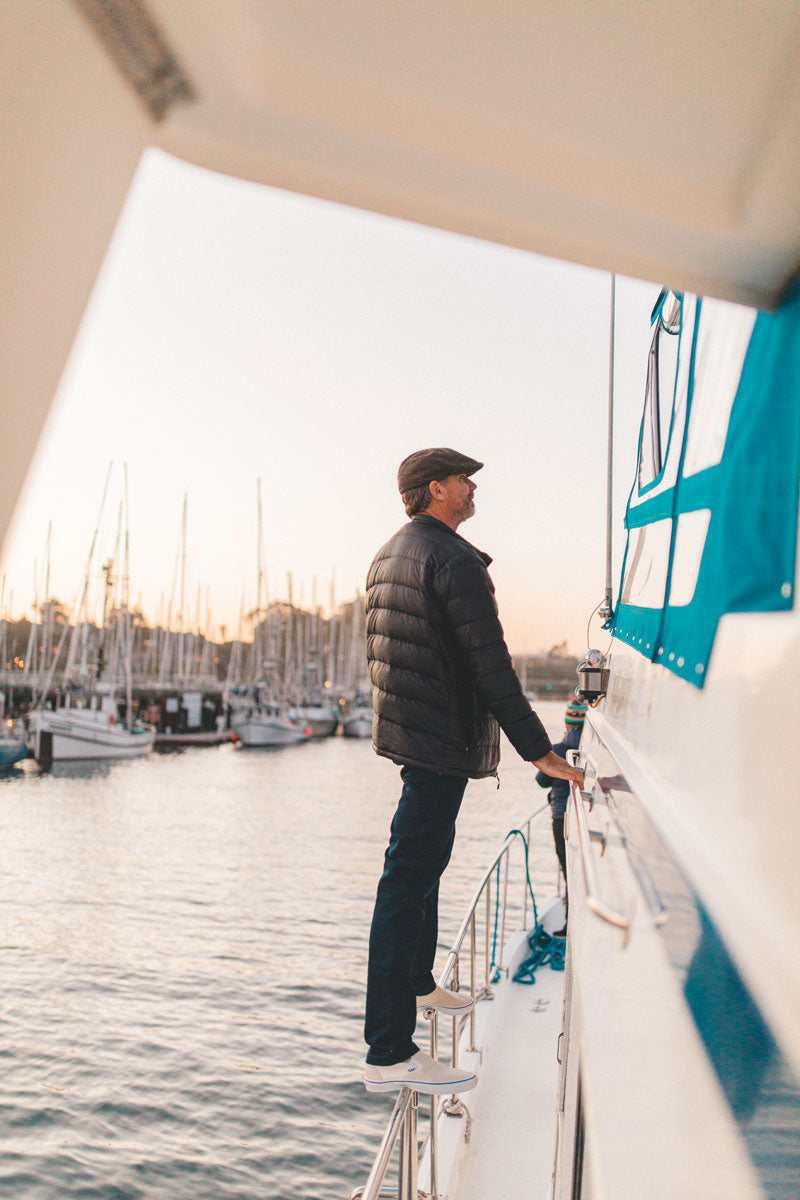 A man standing at the side of the boat wearing a brown men cap