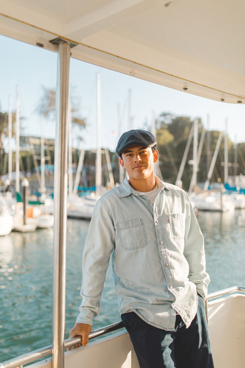 A man standing on a boat wearing a charcoal cap