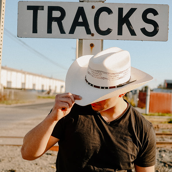 A man wearing black shirt wearing white cowboy hat 