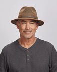 Portrait of a smiling middle-aged man wearing a brown Otis leather hat and a gray henley shirt