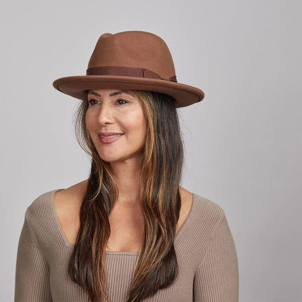 Smiling woman wearing a brown Pablo felt hat and a light brown sweater