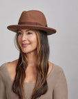 Smiling woman wearing a brown Pablo felt hat and a light brown sweater