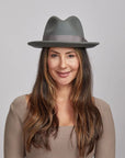 Smiling woman wearing a grey Pablo felt hat and a light brown sweater