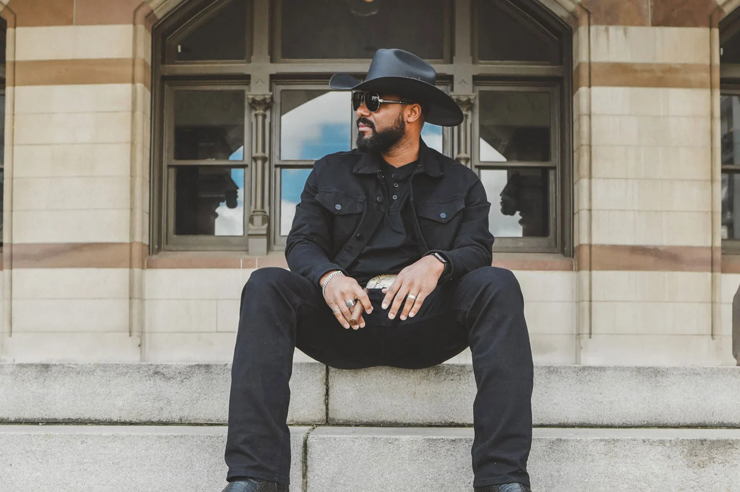 Cowboy sitting on steps wearing the Pioneer mens hat by American Hat Makers