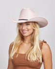 Smiling woman with long blonde hair wearing a pink Pioneer cowboy hat and a brown sleeveless top