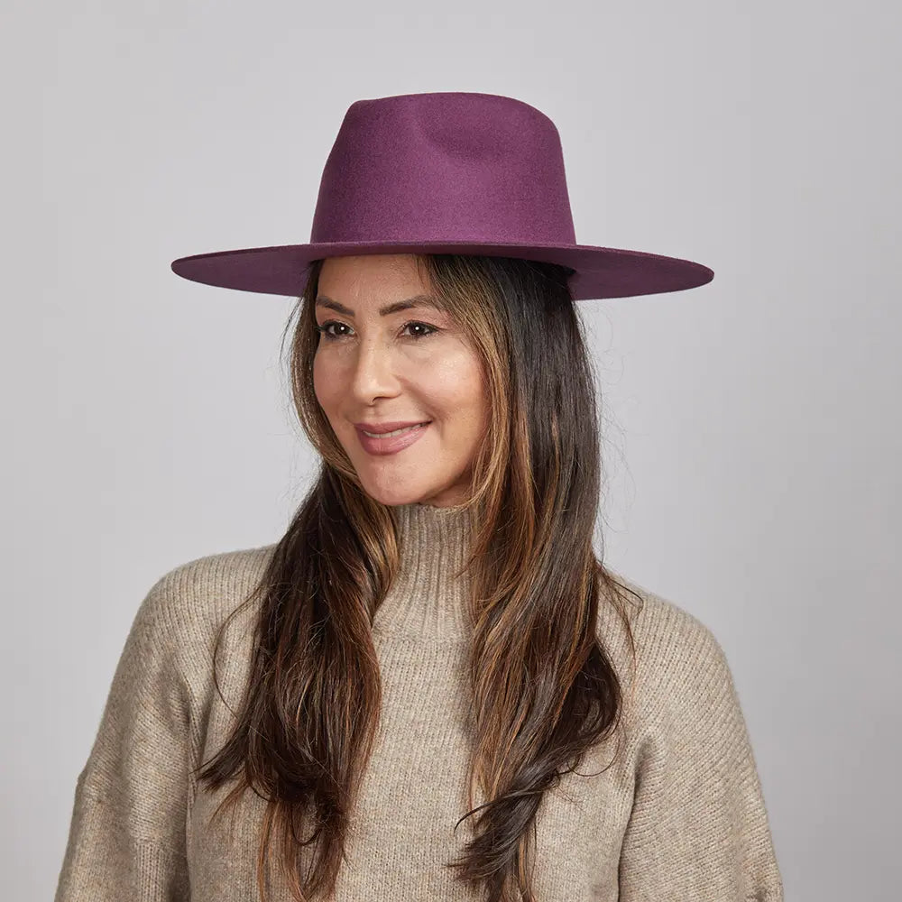 A smiling woman wearing a plum Rancher hat and a beige sweater.