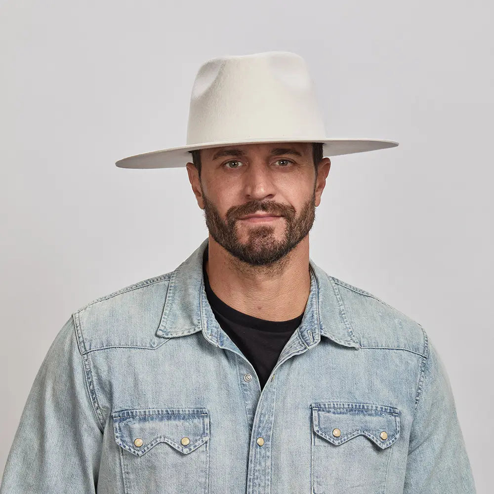 Man with a beard wearing a White Rancher Hat and a denim jacket over a black shirt.