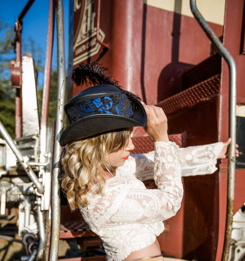 A woman in a white blouse wearing a reversible blue and purple top hat