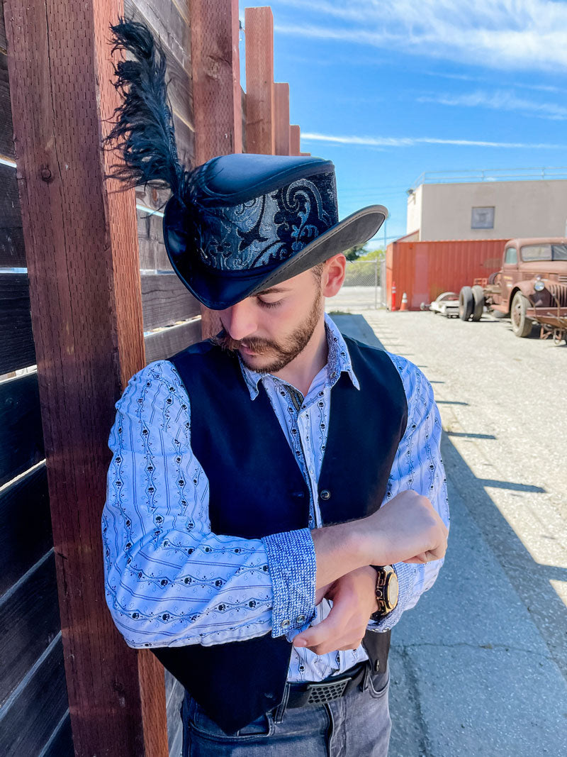 A man standing outdoors wearing a reversible red and silver top hat