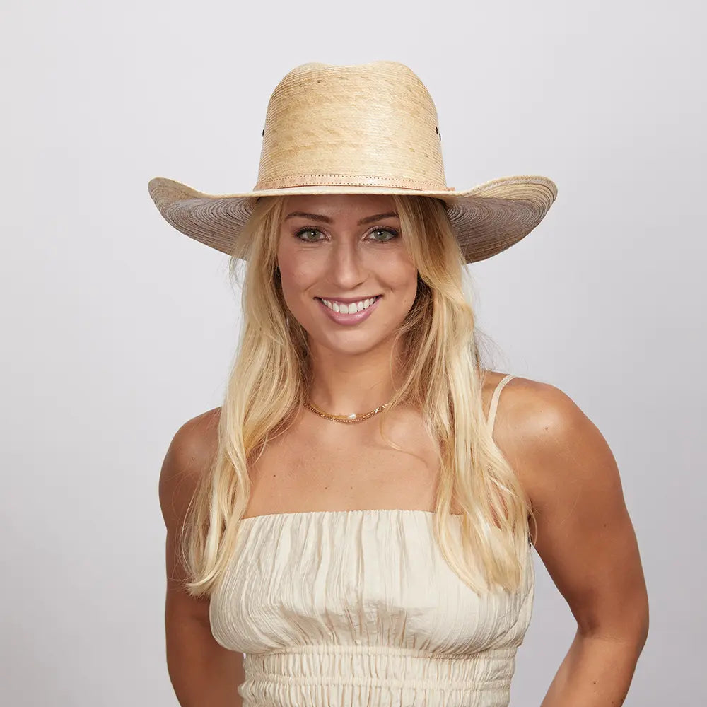 A woman wearing a white top and a cream straw cowboy hat