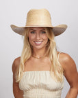 A woman wearing a white top and a cream straw cowboy hat