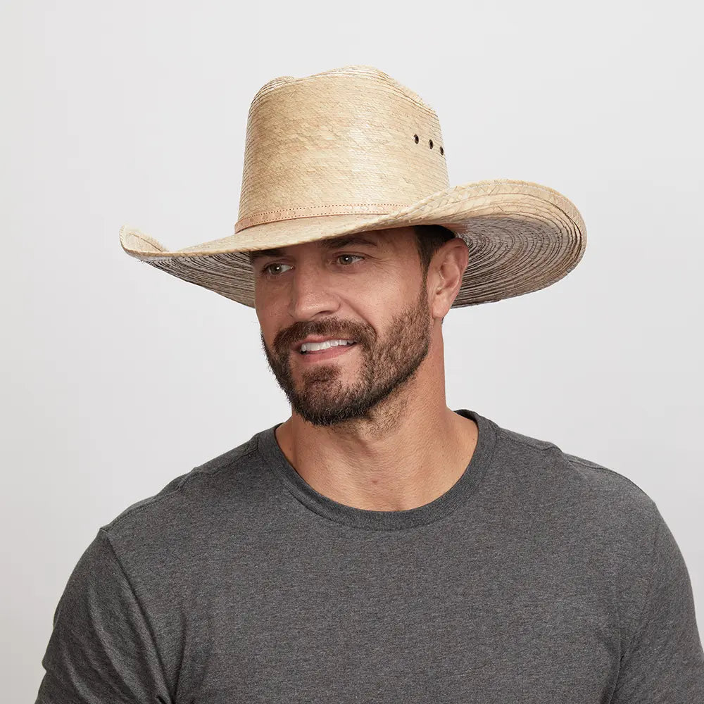 A smiling man looking to the side wearing a straw cowboy hat