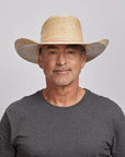 A man in a gray top wearing a cream palm cowboy hat