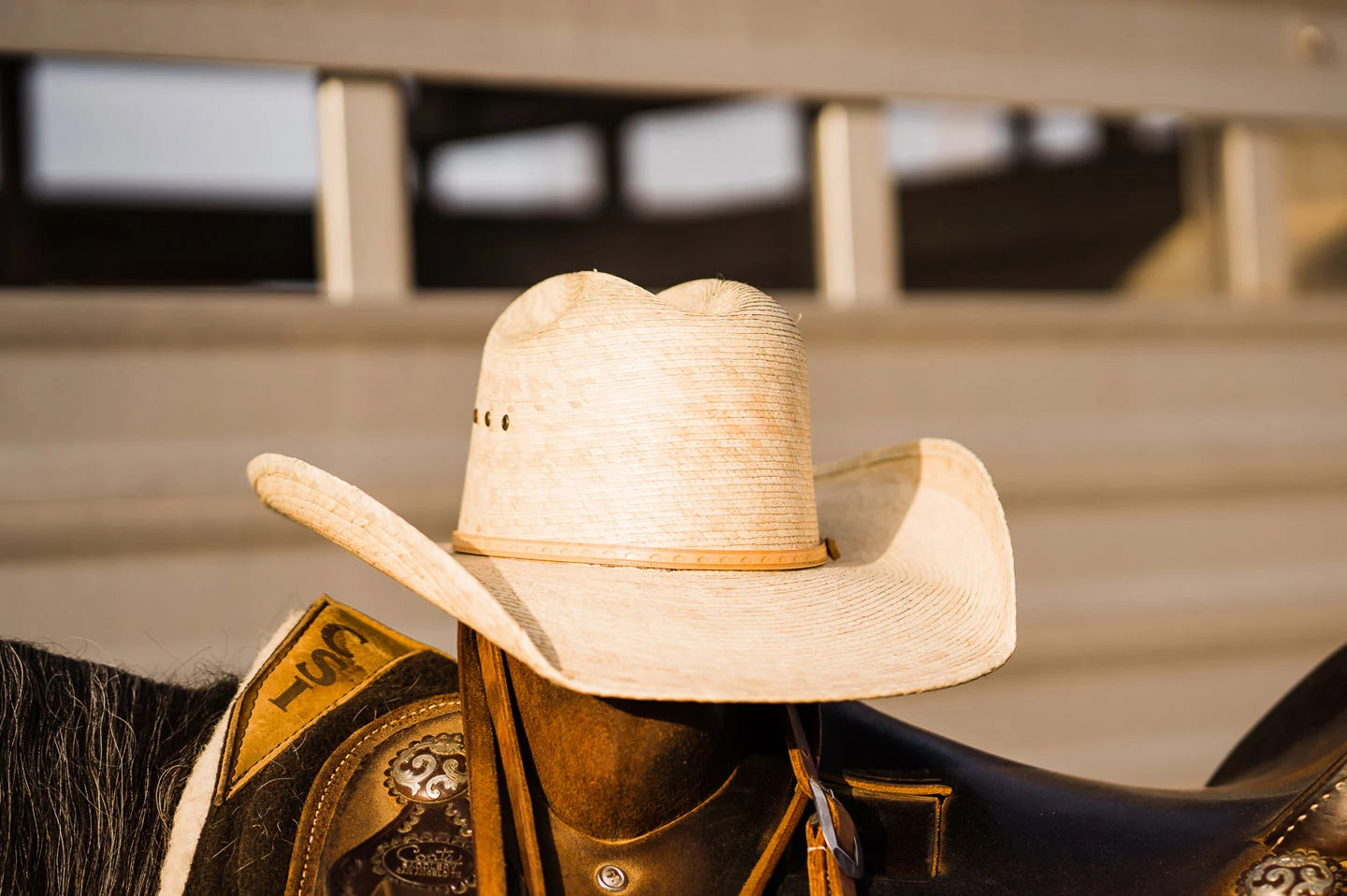 The Ringo mens straw cowboy hat by American Hat Makers sitting on saddle on horse